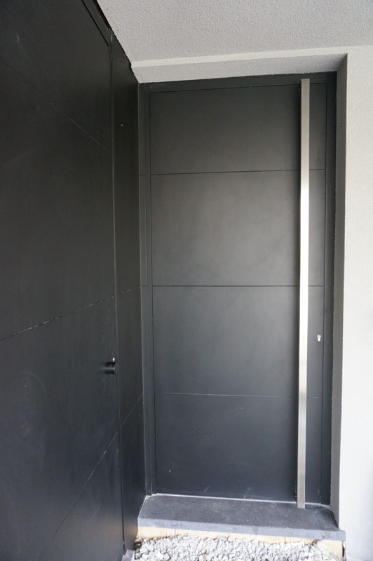 Strakke, matzwarte aluminium voordeur met lange verticale greep