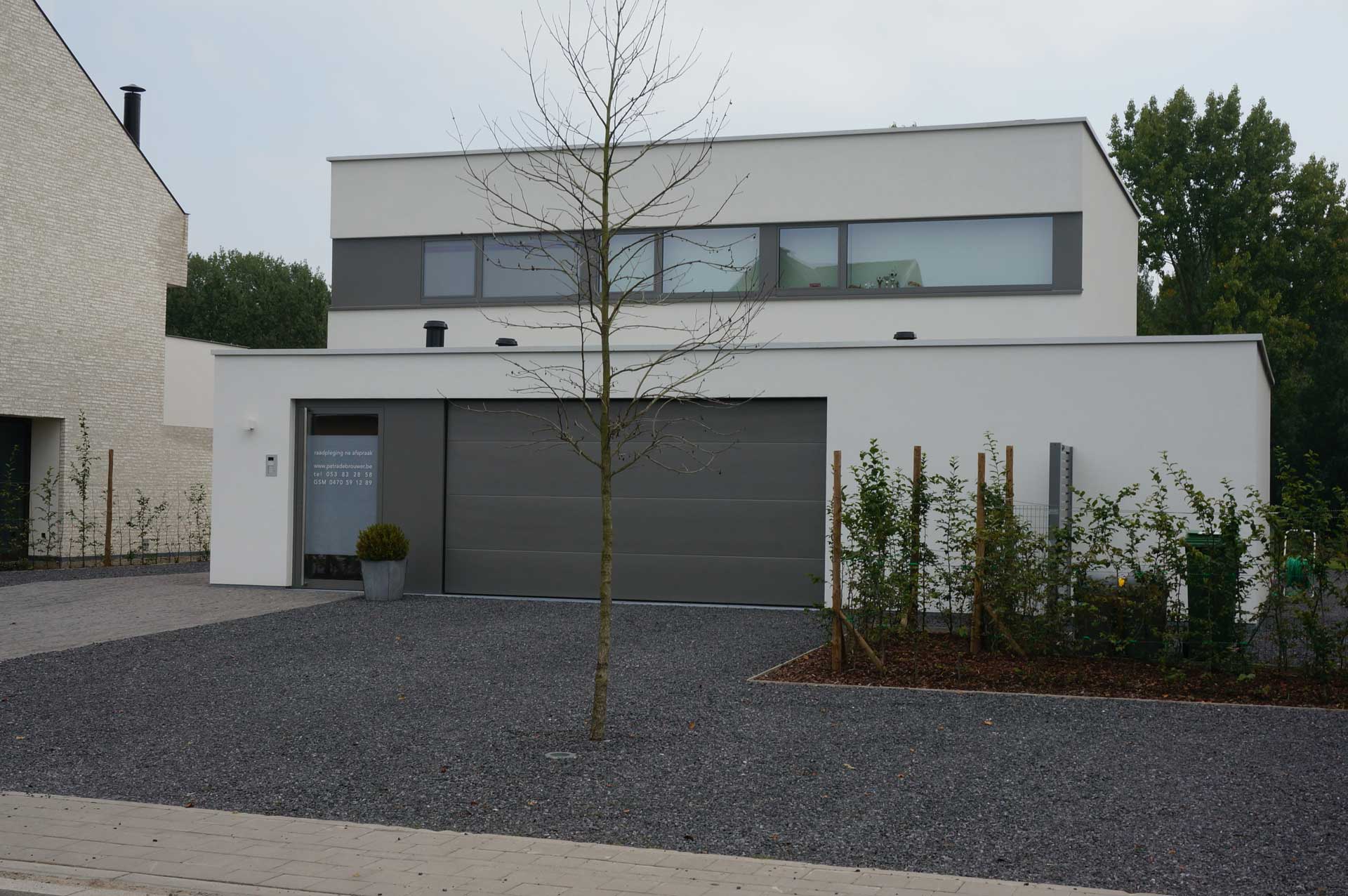 Moderne woning met brede glasstroken en grijze aluminium ramen voor een strakke, tijdloze uitstraling