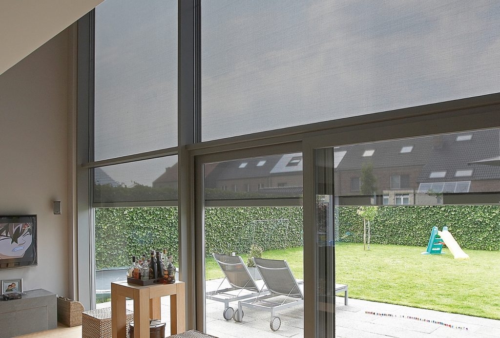 Grote aluminium ramen met screens die zonlicht filteren en uitkijken op de tuin